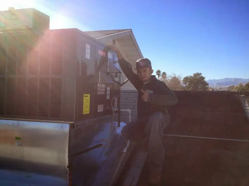 HVAC technician performing AC Tune-Up on a rooftop unit in South River